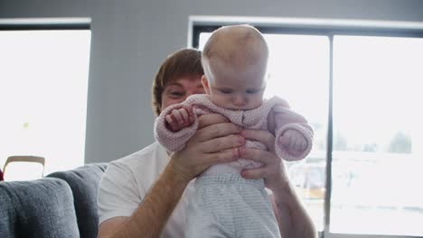 Happy-cheerful-dad-showing-baby-daughter-at-camera